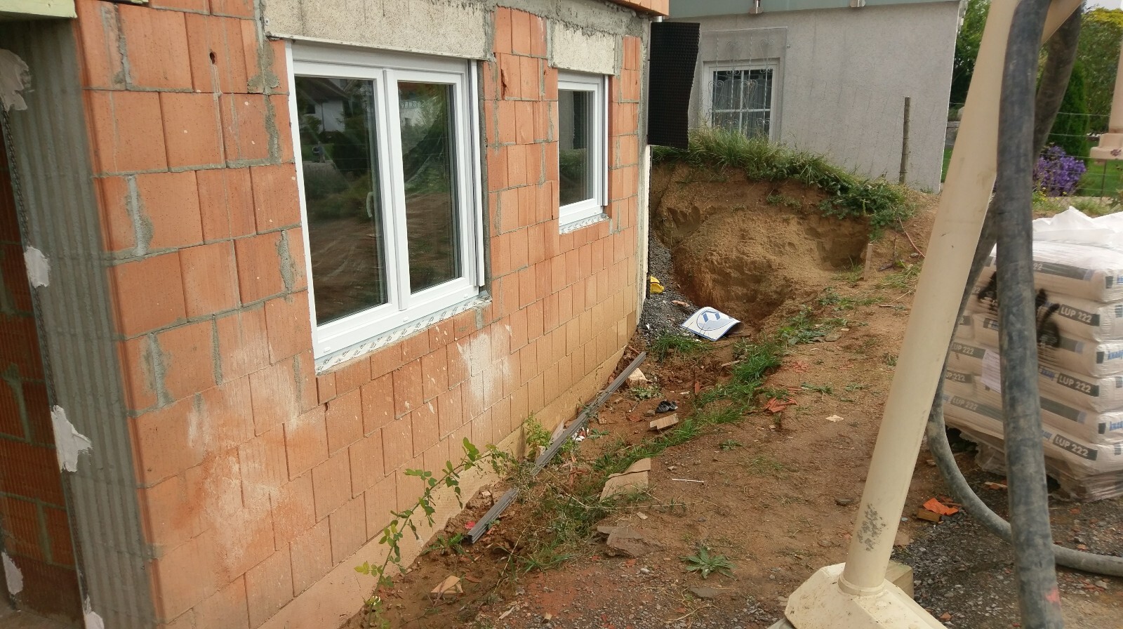 Außenwand aus roten Ziegelsteinen mit Fenstern an einer Baustelle