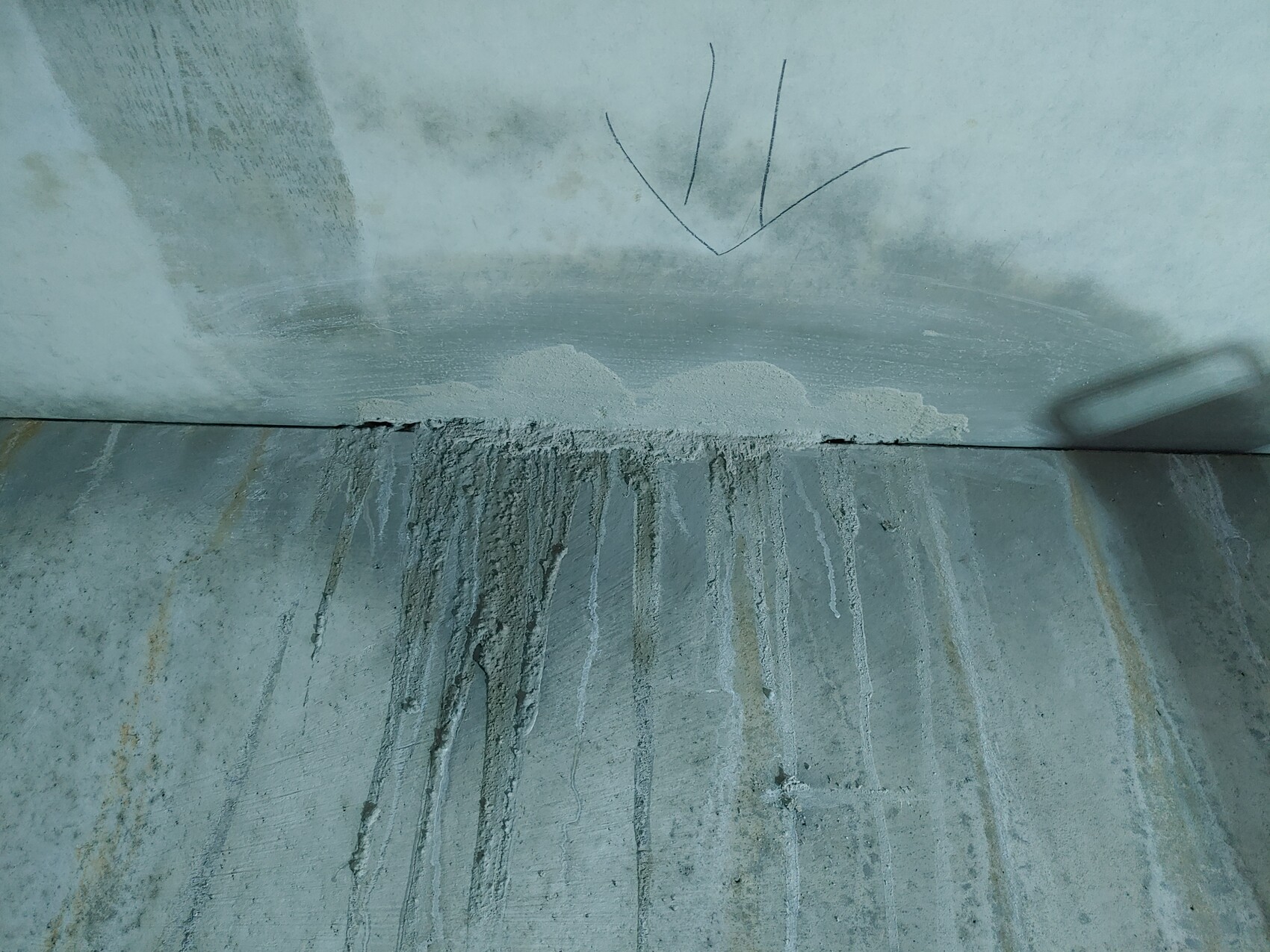 Betonwand mit horizontaler Fuge, Kalk- und Feuchtigkeitsablagerungen sowie vertikalen Tropfspuren.