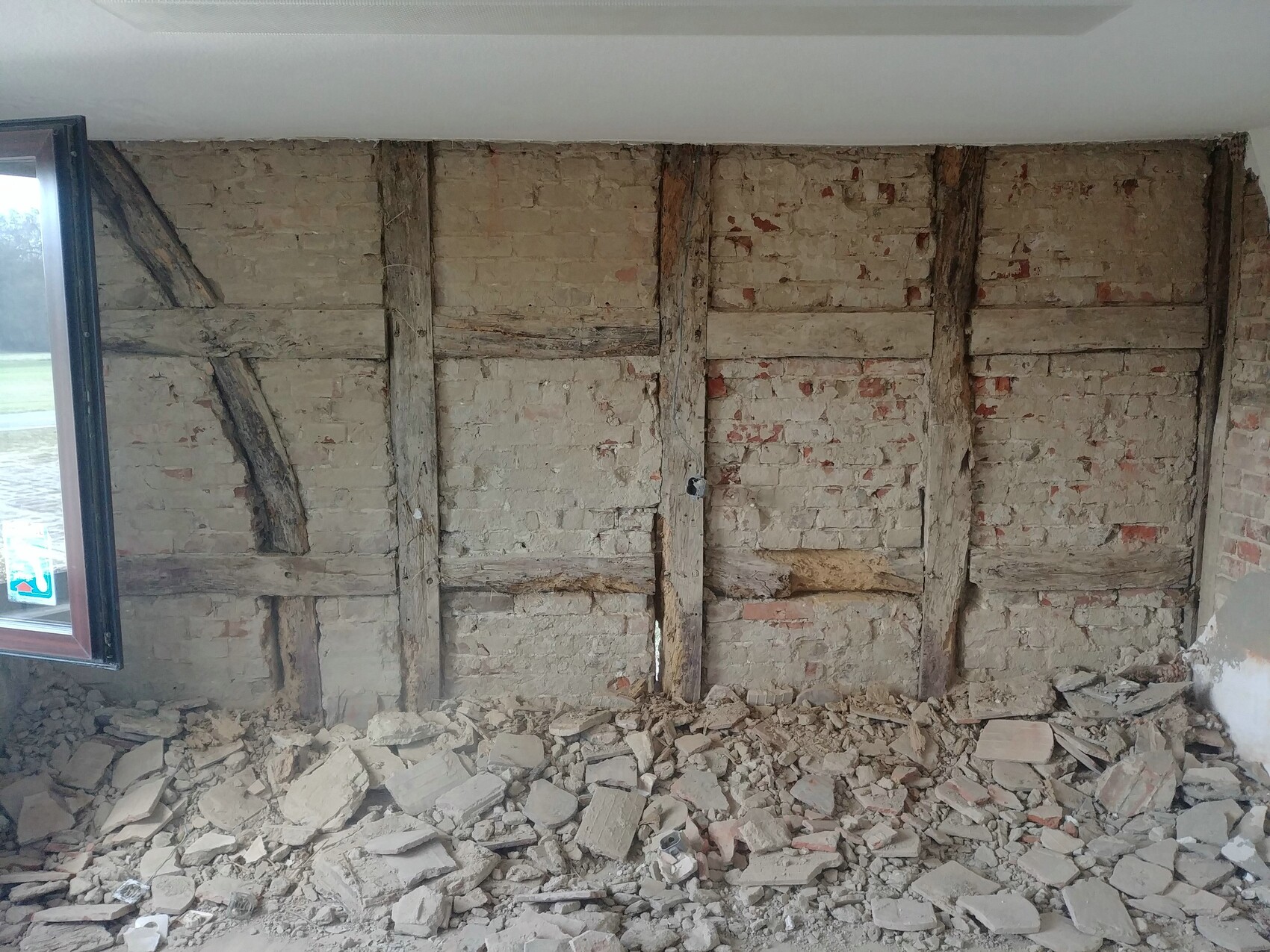 Innenraum mit freigelegter Ziegelwand, Holzrahmen und Baustellen-Schutt