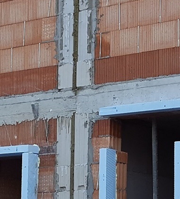 Rohbau-Baustelle mit Ziegelwänden, Betonfassade und Fensteröffnung sichtbar