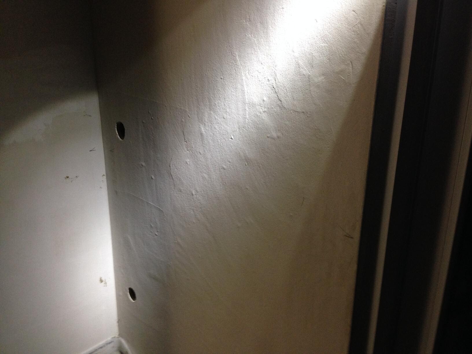 Unbearbeitete Innenwand mit Bohrlöchern und rauem Putz