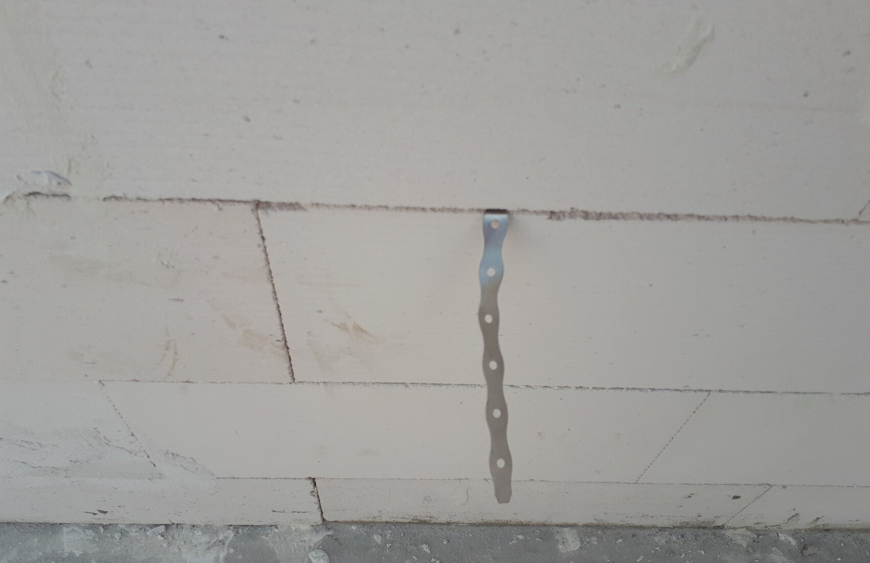 Rohbau-Wand aus Betonsteinen mit vertikal montiertem perforiertem Montageblech