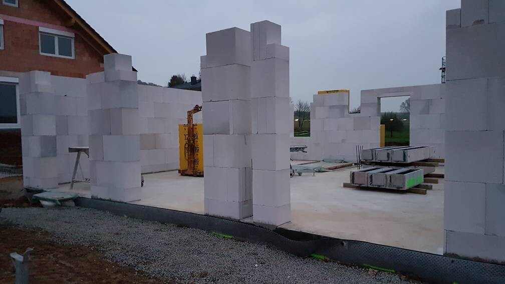 Baustelle mit weißen Blöcken als Wände, gelbem Baugerät und Paletten mit Material.