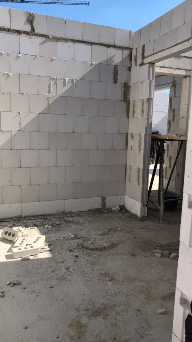 Baustelle: Innenraum eines Neubaus mit weißen Betonblöcken, Türöffnung und Schutt.