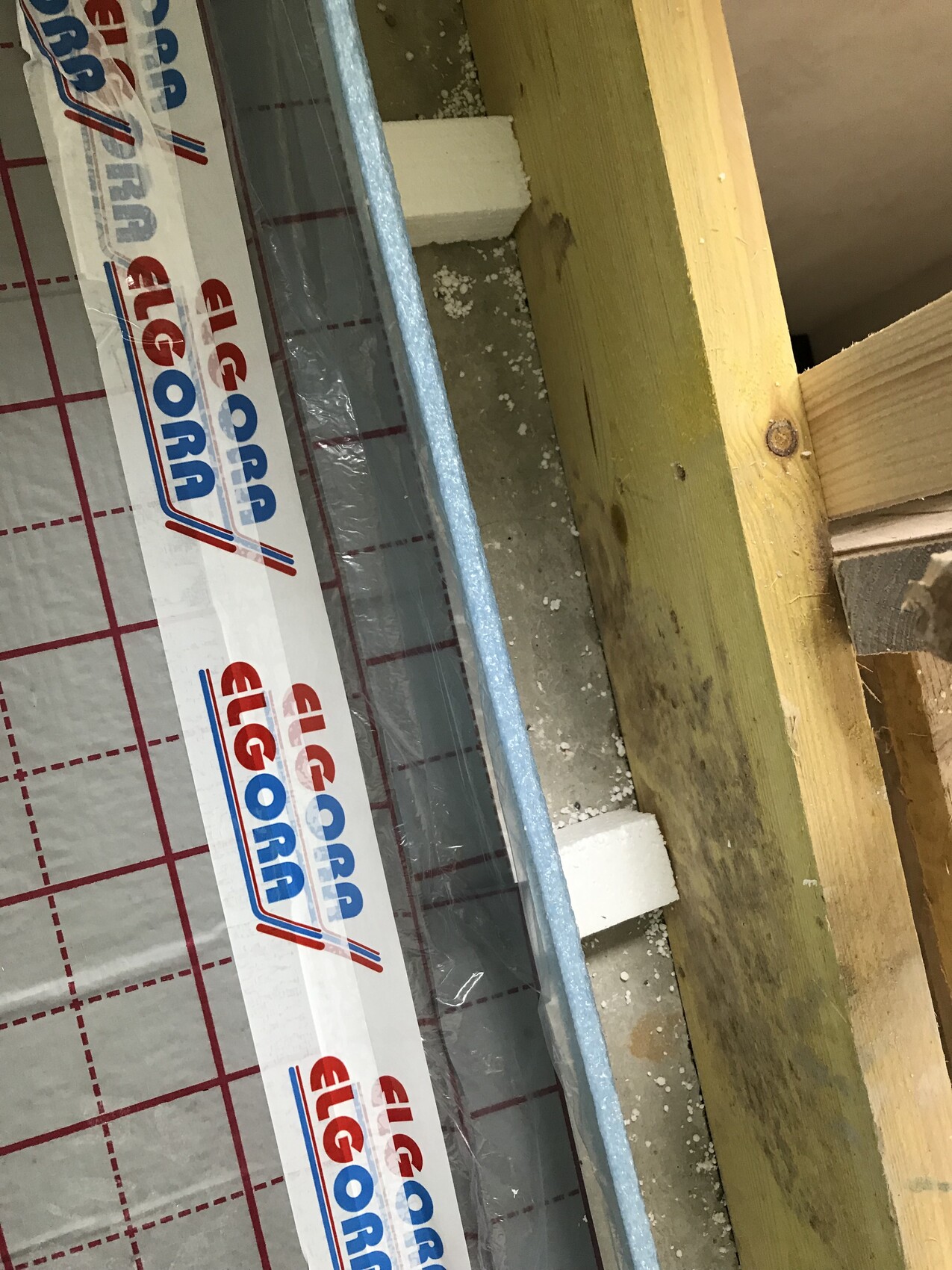 Baustelle mit Holzständerwerk, Dämmmaterial, Betonboden und Verpackungsmaterial