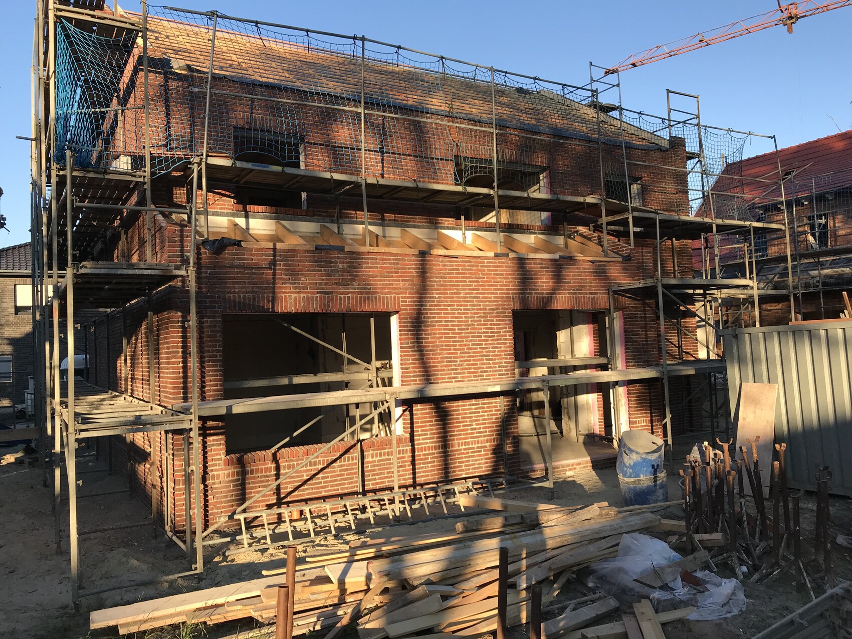 Baustelle mit rohem Ziegelhaus und Gerüst um einen zweigeschossigen Rohbau im Baufortschritt