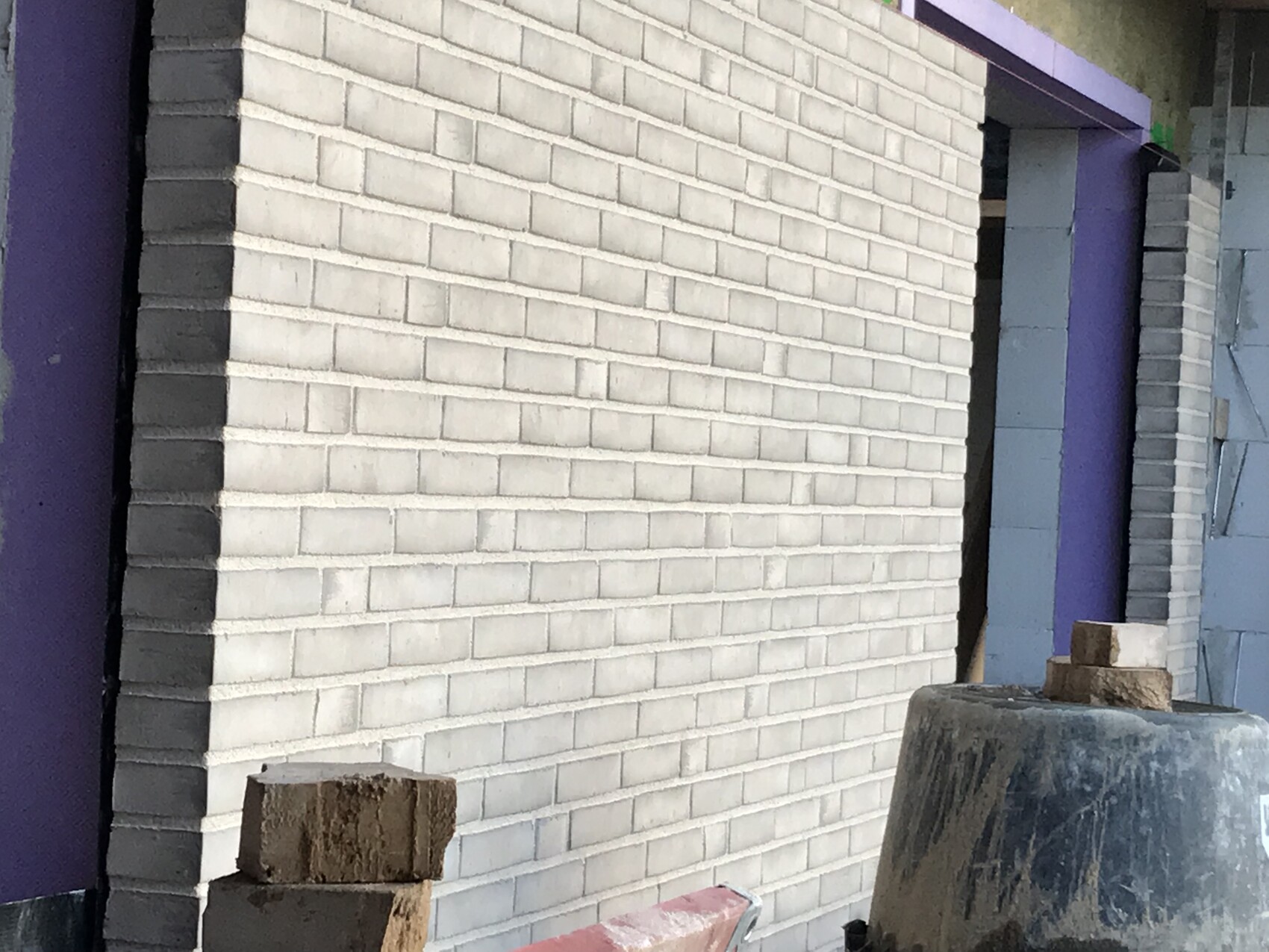 Baustelle mit Ziegelwand eines Rohbaus und Baumaterialien davor