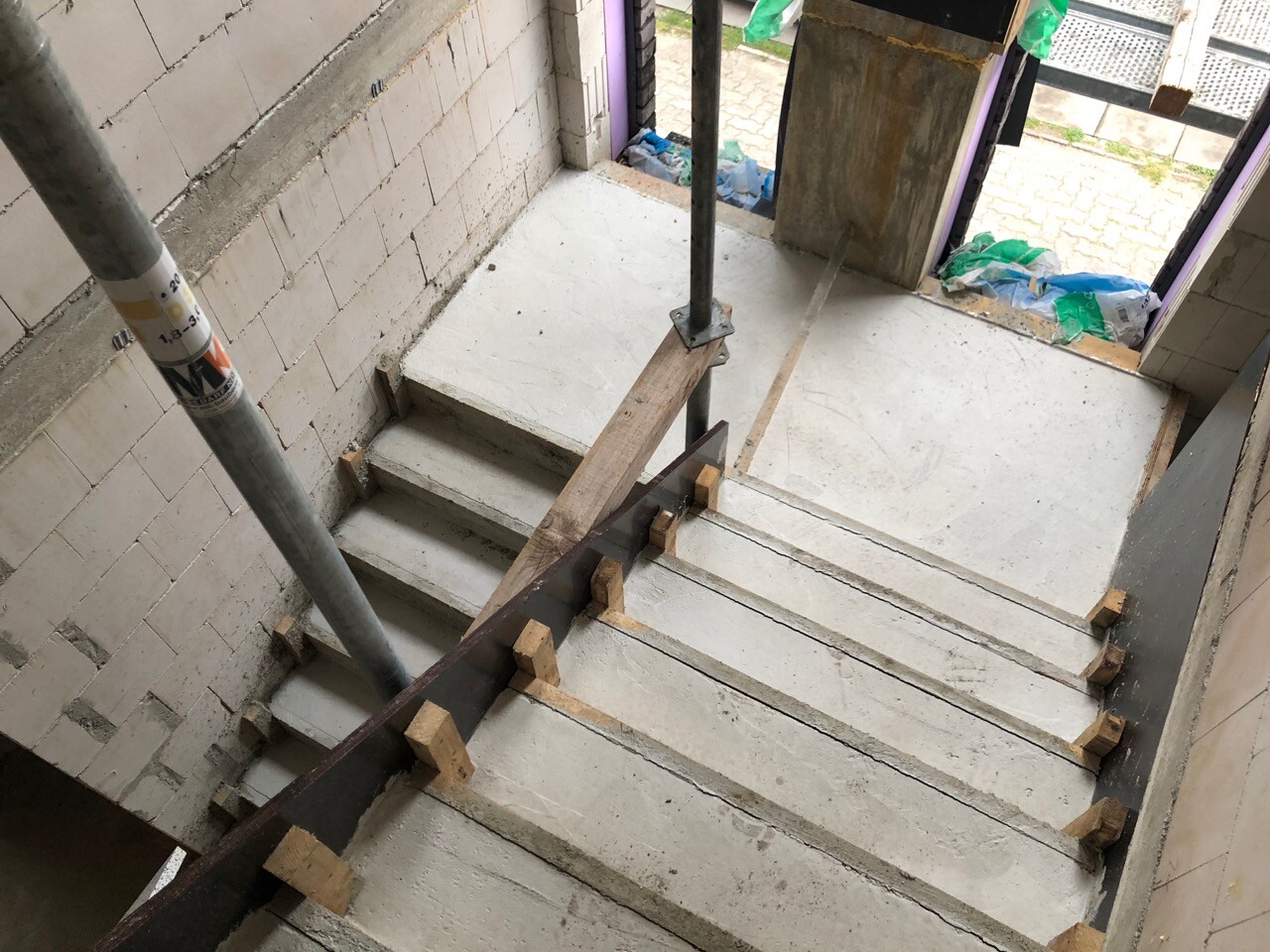 Unfertige Betonstufen-Treppe im Bau mit provisorischem Holzhandlauf und Stahlstütze