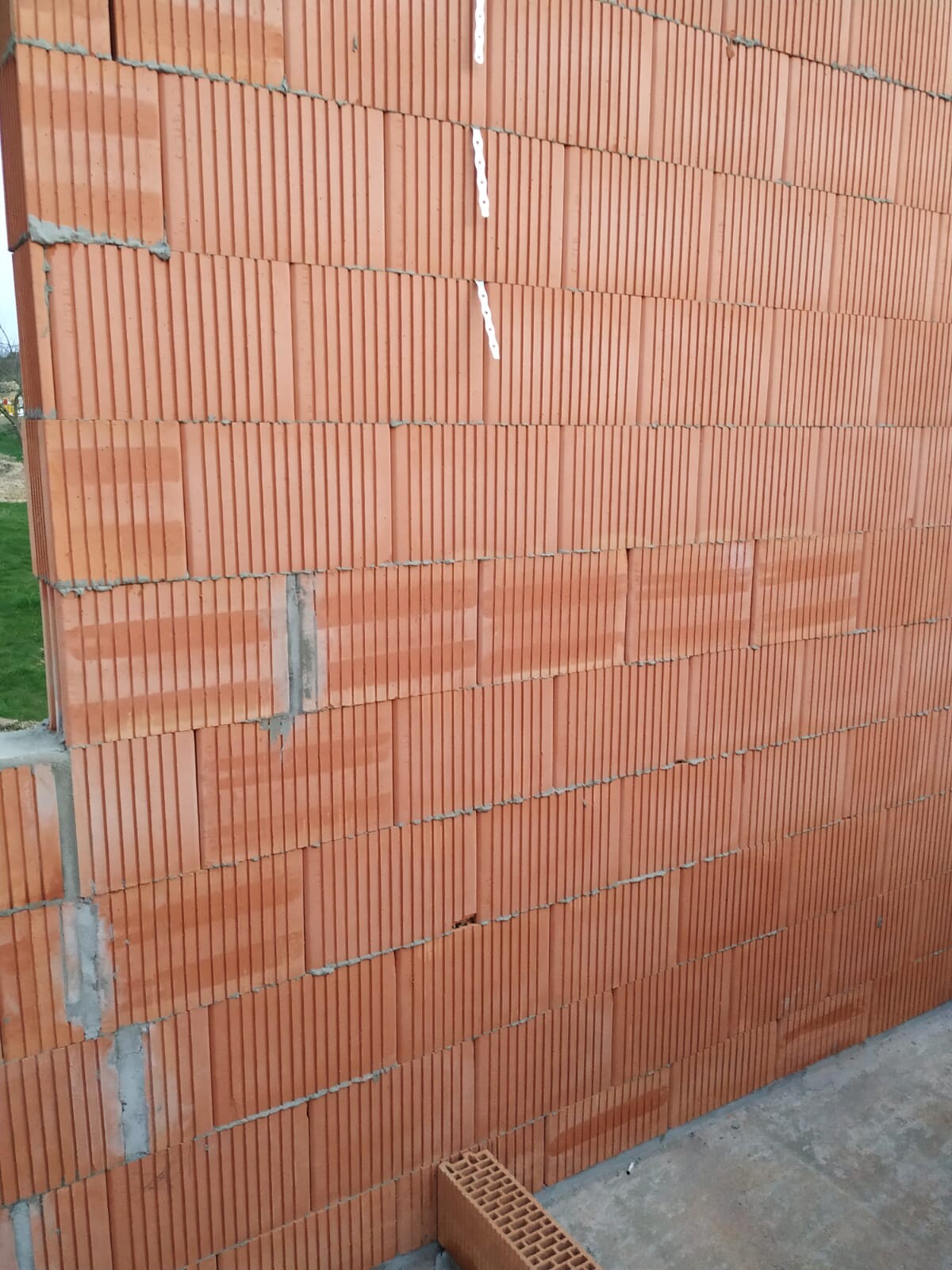 Neu errichtete rote Ziegelwand aus Hohlziegeln, sichtbare Mörtelfugen, Betonboden unten