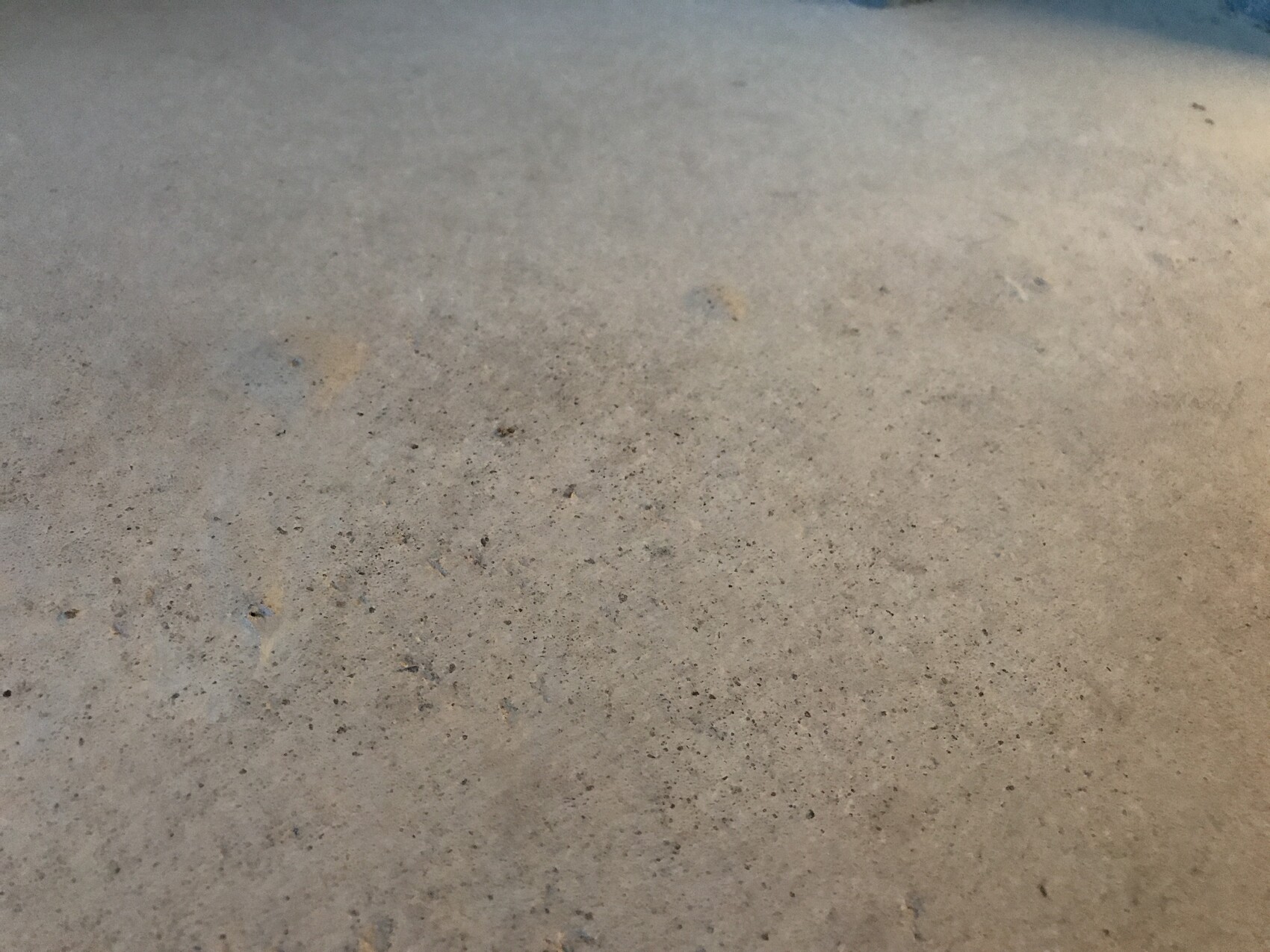 Nahaufnahme einer rauen Betonoberfläche mit kleinen Poren und Flecken.