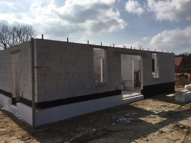 Rohbau aus Betonblöcken mit Fenster- und Türöffnungen auf Baustelle.