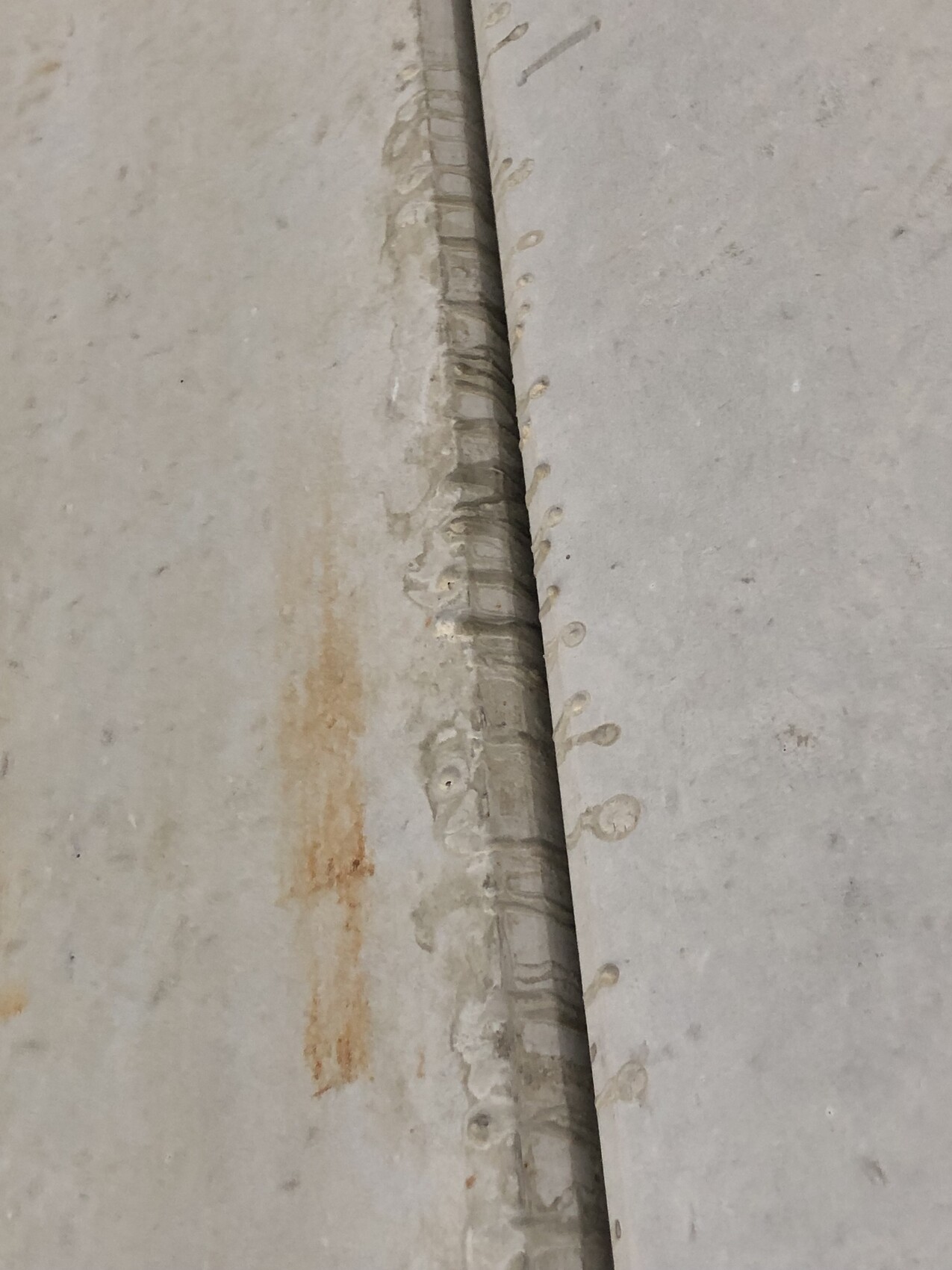 Spalte zwischen zwei Betonplatten; Rostspuren links, glatte Fläche rechts, Rand mit Nieten