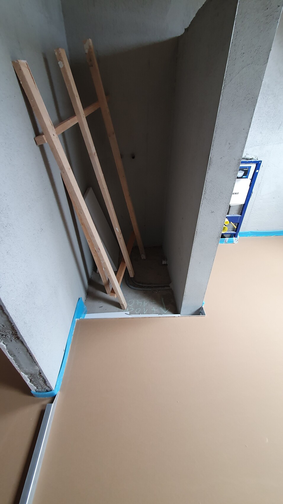 Unfertiger Baubereich: Mehrere Holzbalken lehnen gegen eine Wand; Boden mit blauer Schutzfolie.