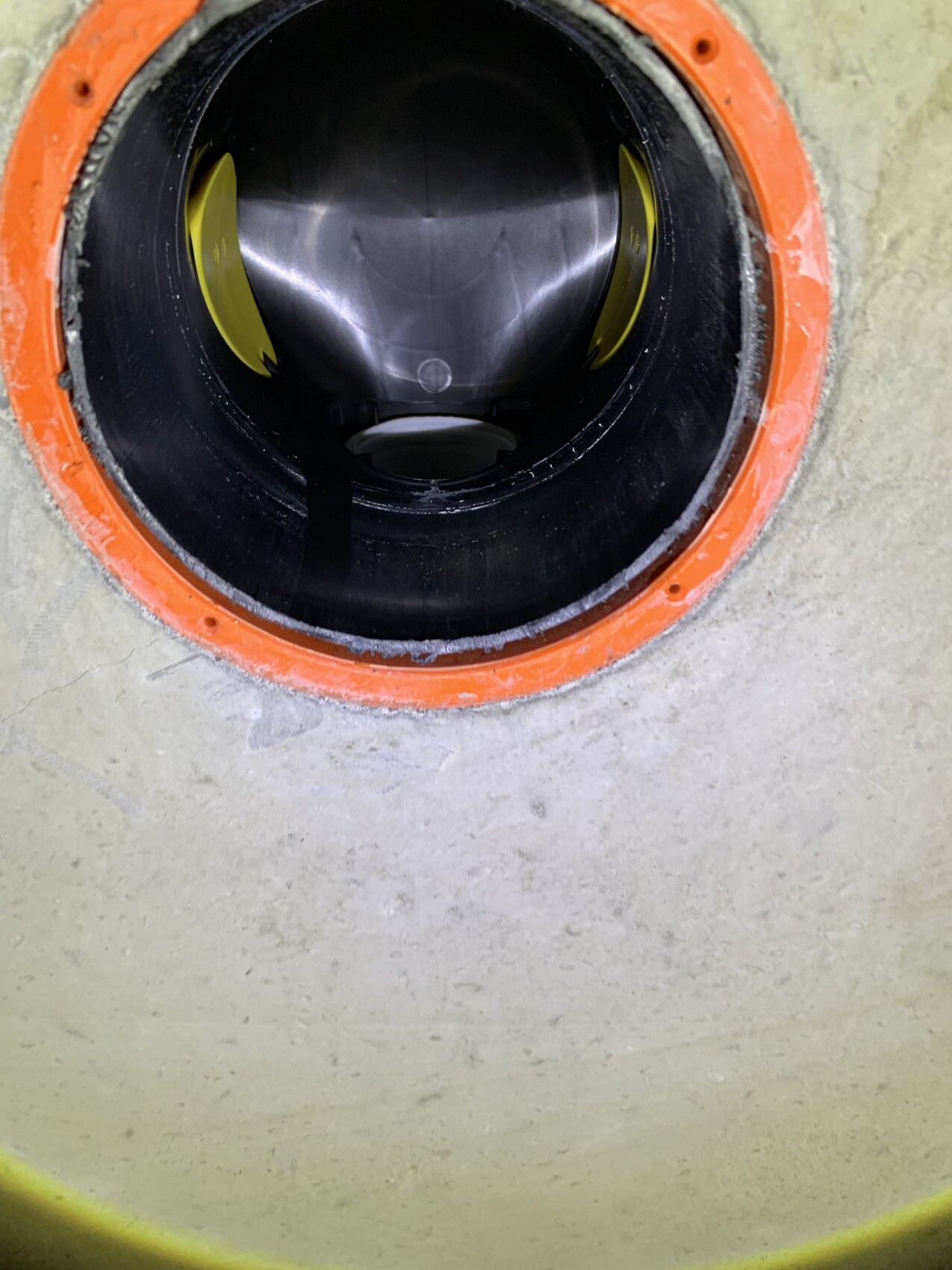 Rundes Rohr mit orangefarbener Dichtung; schwarzes Innenrohr und Metallwand sichtbar.