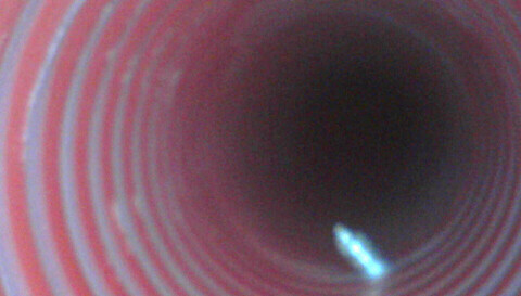 Roter spiralförmiger Rohrquerschnitt mit dunklem Zentrum und Lichtreflexen