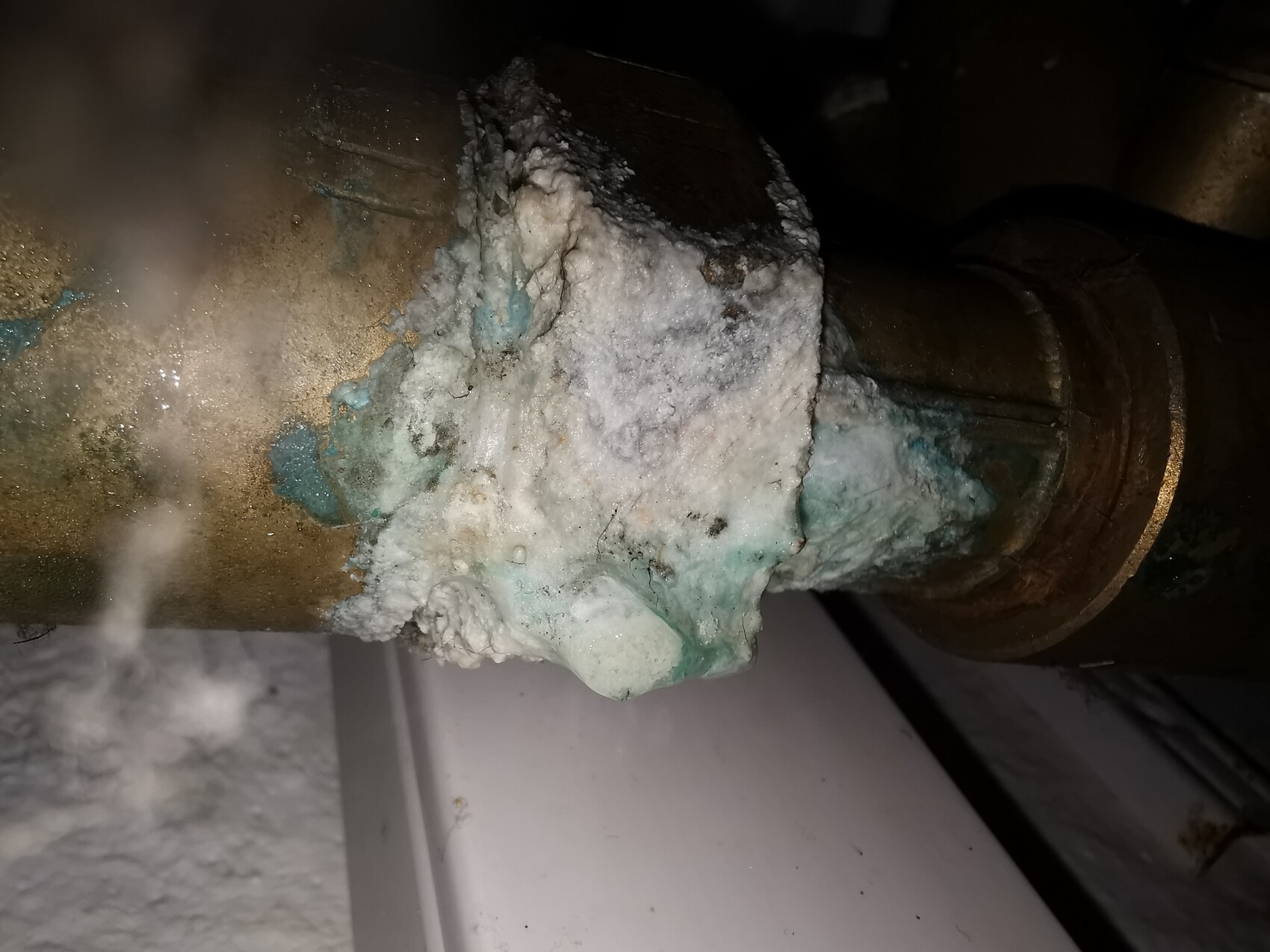 Kupferrohr mit weißem mineralischem Belag und gruen-bläulicher Korrosion an der Rohrverbindung