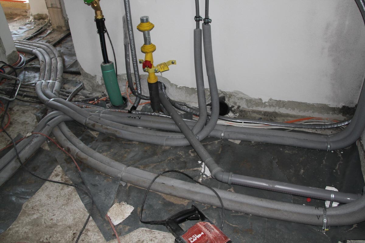 Kellerbaustelle mit Rohren, Ventilen und Kabeln für Haustechnikinstallation