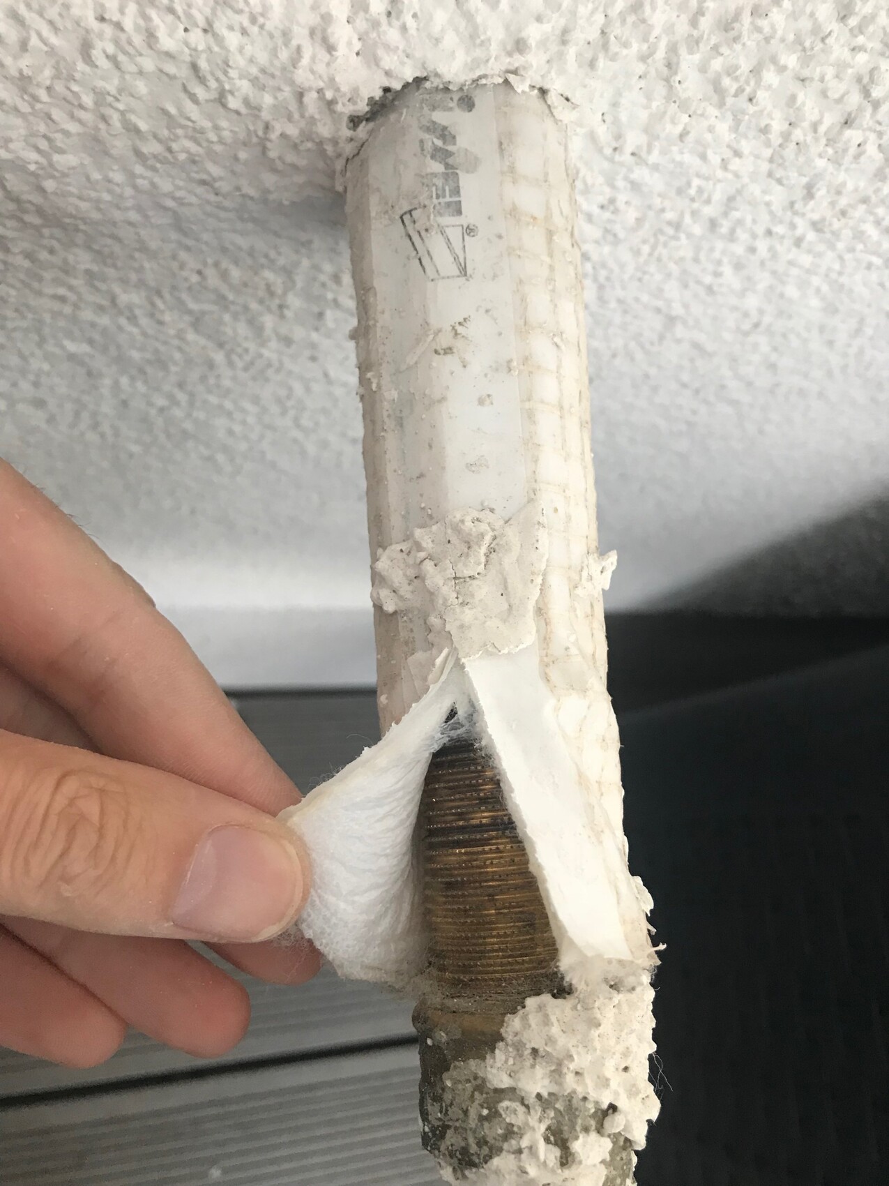 Nahaufnahme einer verputzten Rohrverbindung mit Korrosion.