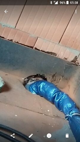 Blaue Kunststoffrohrverlegung durch Wandöffnung während Bauarbeiten