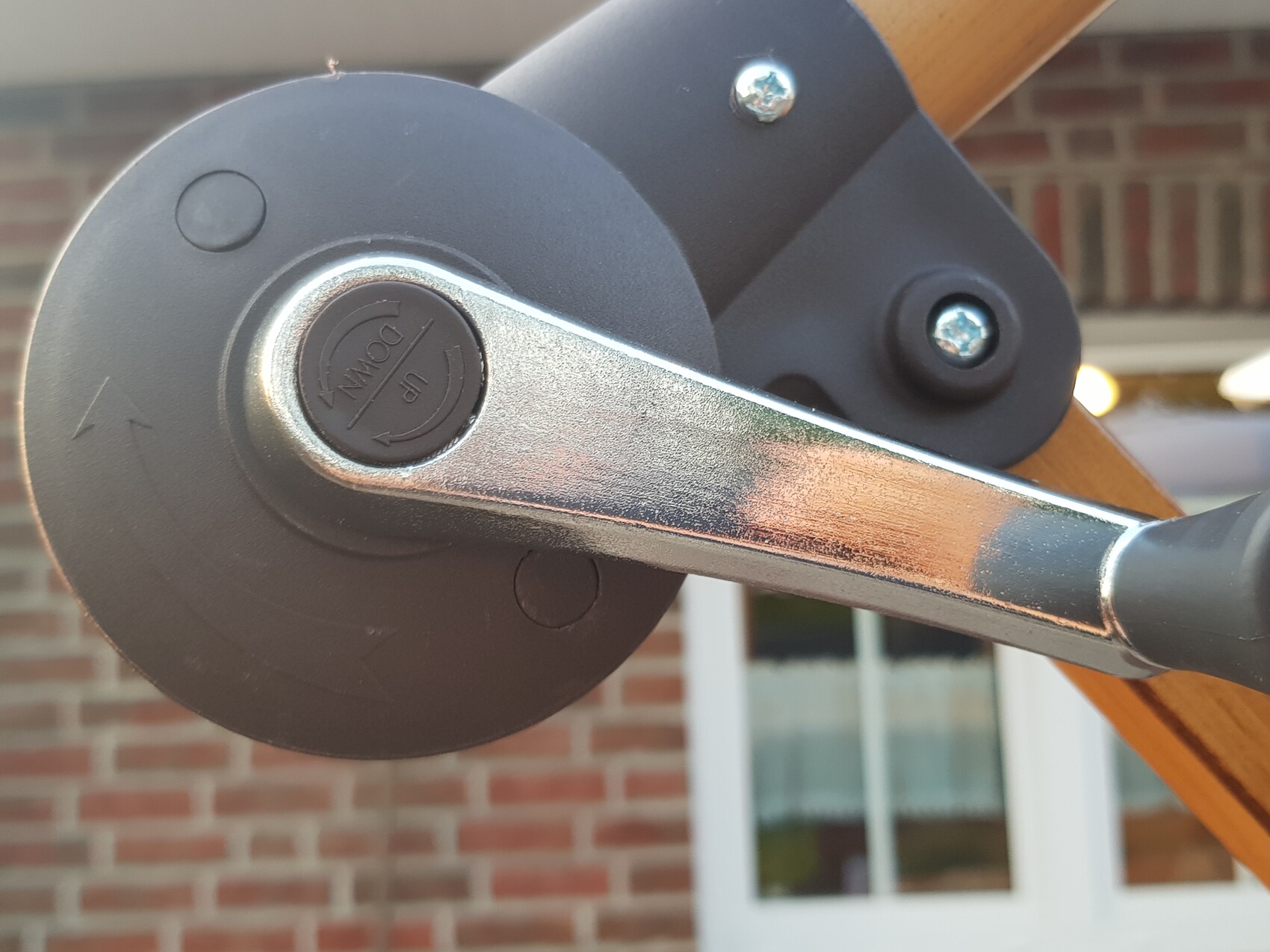 Nahaufnahme eines manuellen Sonnenschirm-Kurbel: runde schwarze Scheibe, Metallhebel.