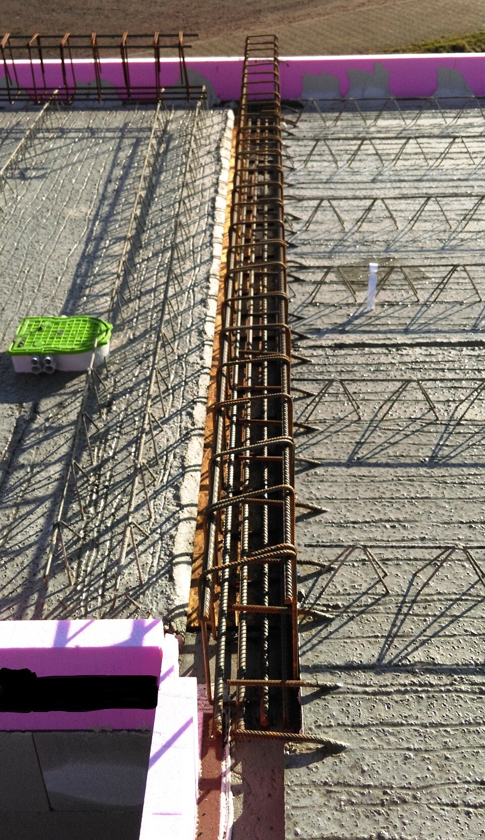 Bewehrungsstahl-Gitter auf Betonboden mit pinkem Rand; zentrale senkrechte Bewehrung, grüne Box links.
