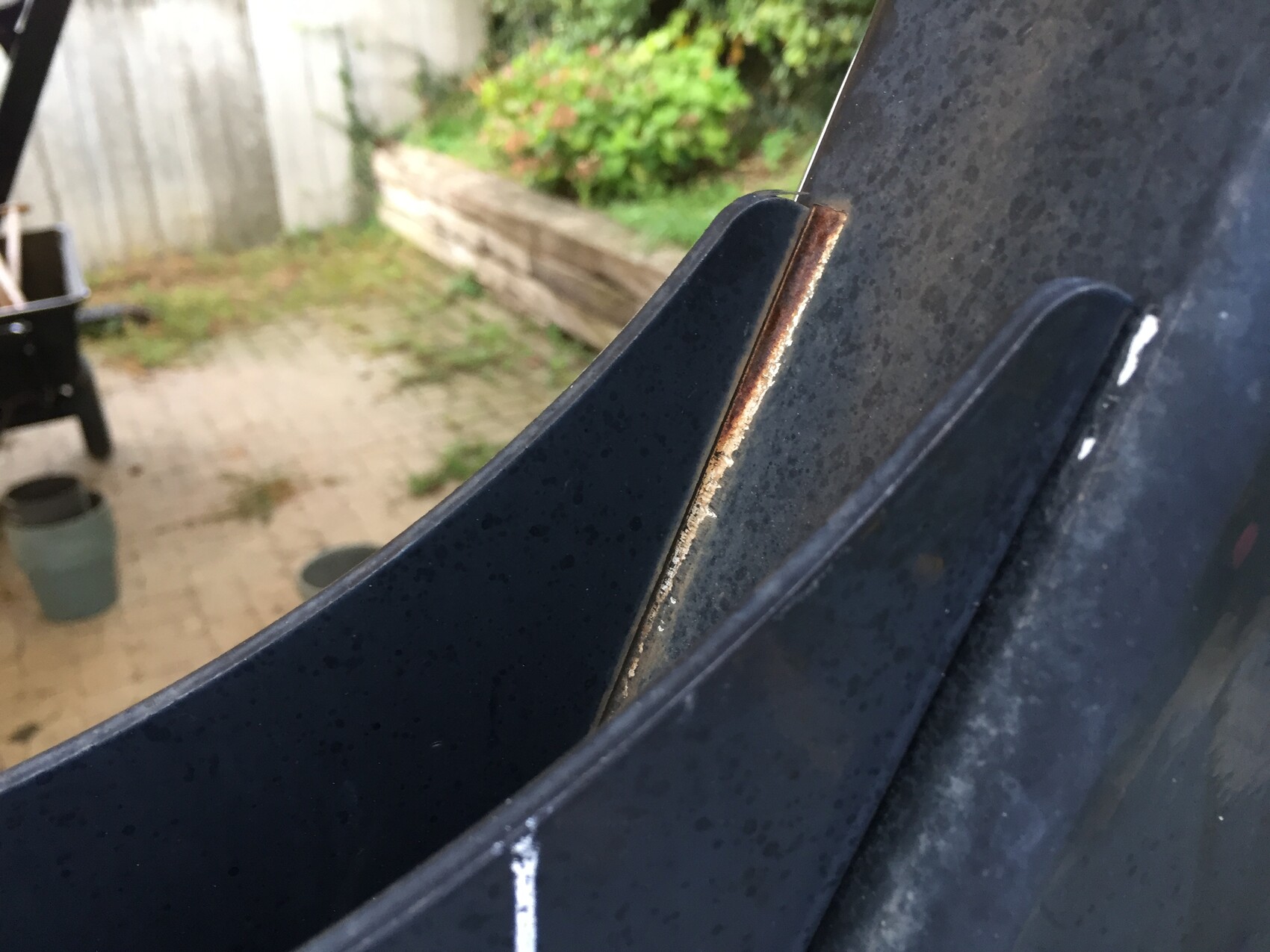 Nahaufnahme einer rostigen Kante am Autotürrahmen, draußen im Garten.