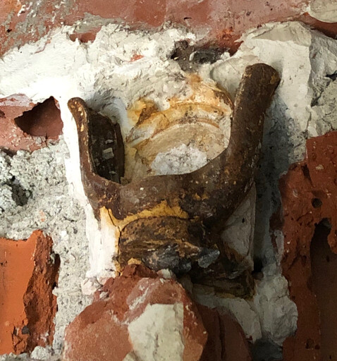 Rostige Klemmvorrichtung in einer Rohbauwand aus Ziegeln