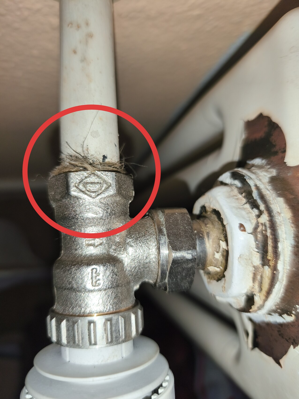 Unterseite eines Sanitärsystems: rostige Verbindung, Dichtung, Wandhalterung sichtbar