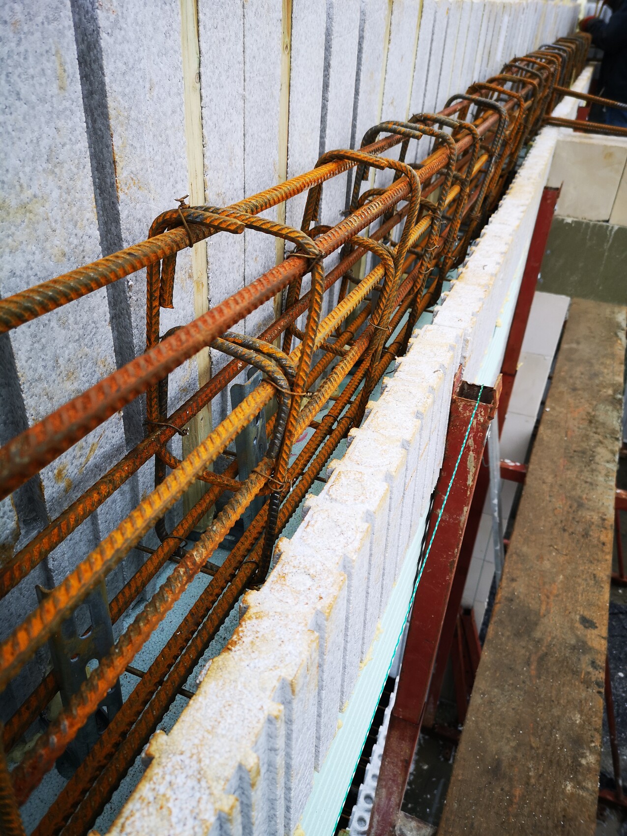 Rostige Bewehrungsstäbe in einer Betonwand-Schalung auf einer Baustelle.