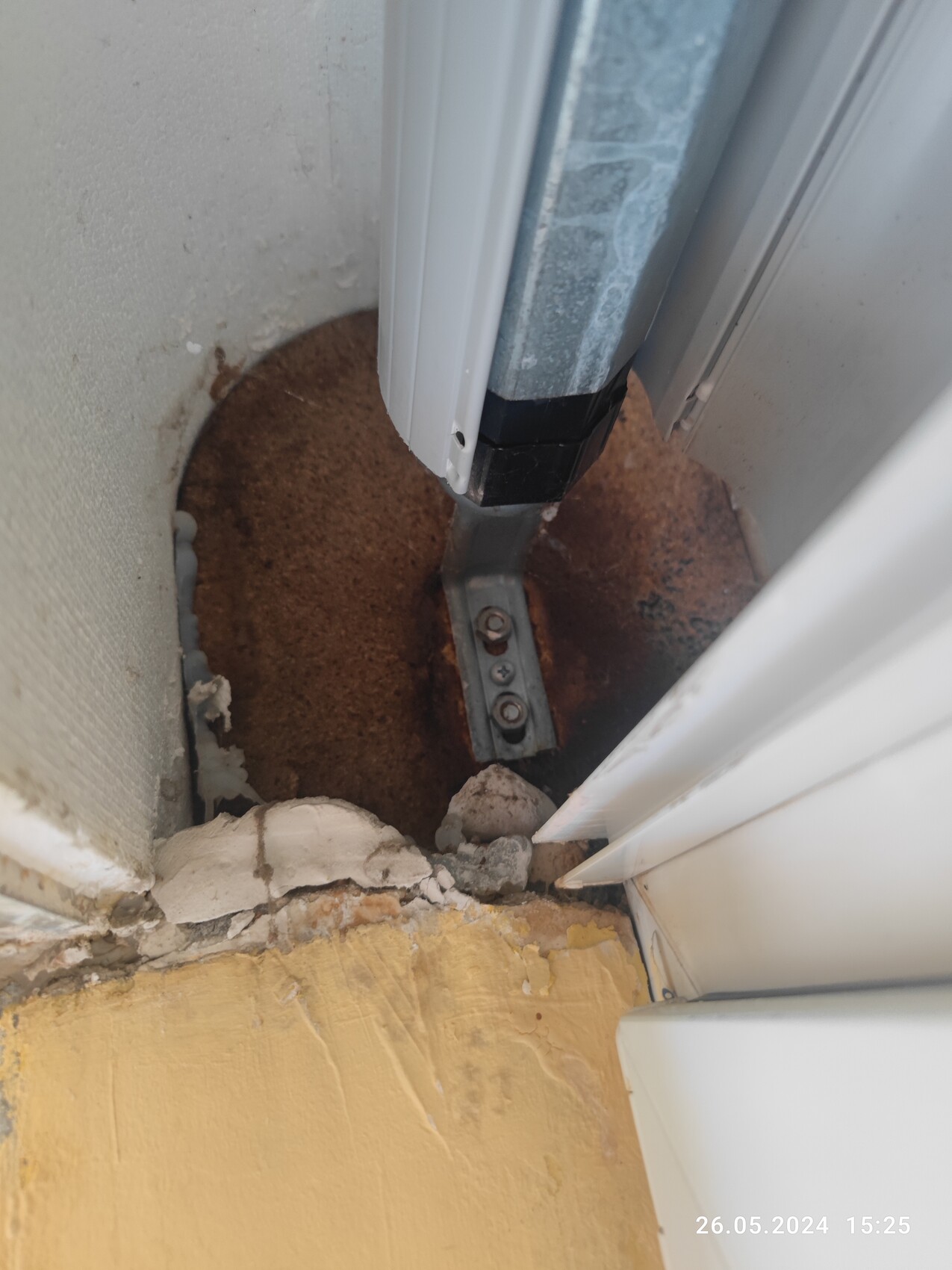 Unterer Türschweller mit rostiger Metallführung, Schrauben und bröckelndem Putz.