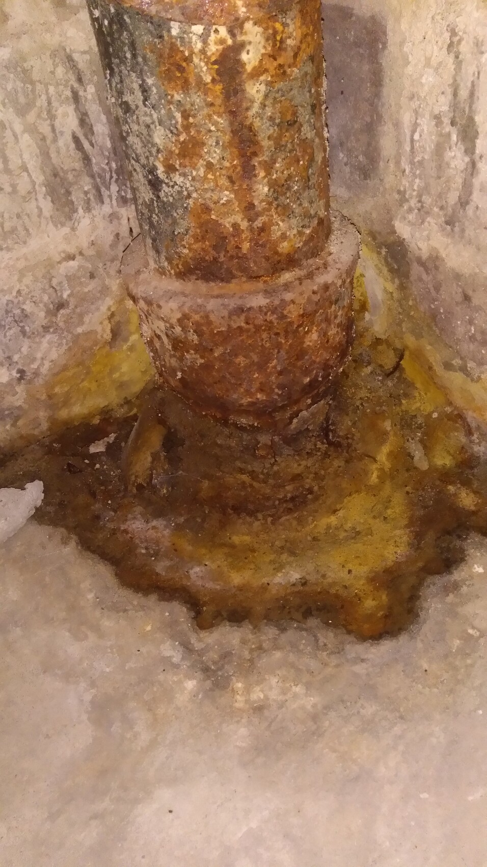 Rostiges Rohr im Kellerboden mit Feuchtigkeit und Wasserschaden.