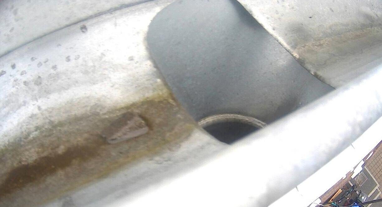 Nahaufnahme eines rostigen Abflussrohrs mit Rostflecken an Metalloberfläche