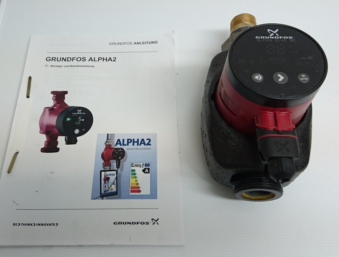 Rote Grundfos Alpha2 Pumpe neben Anleitung auf hellem Hintergrund