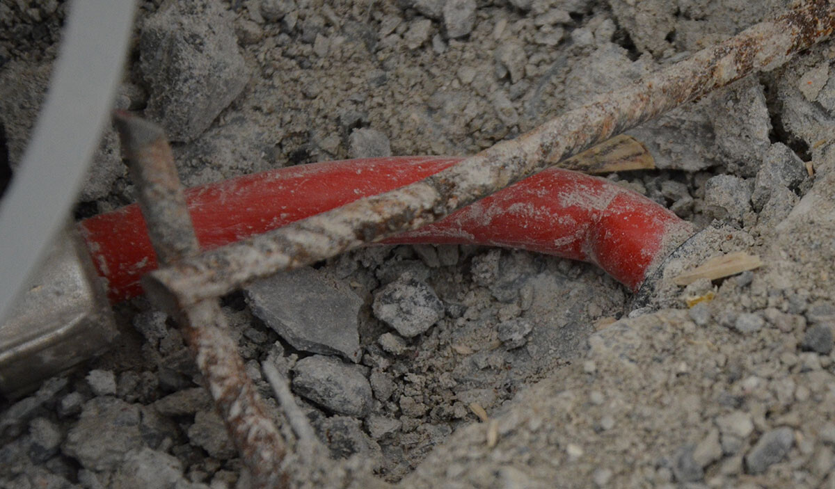 Nahaufnahme einer Baustelle mit roter Kabelleitung, Draht und grobem Schutt