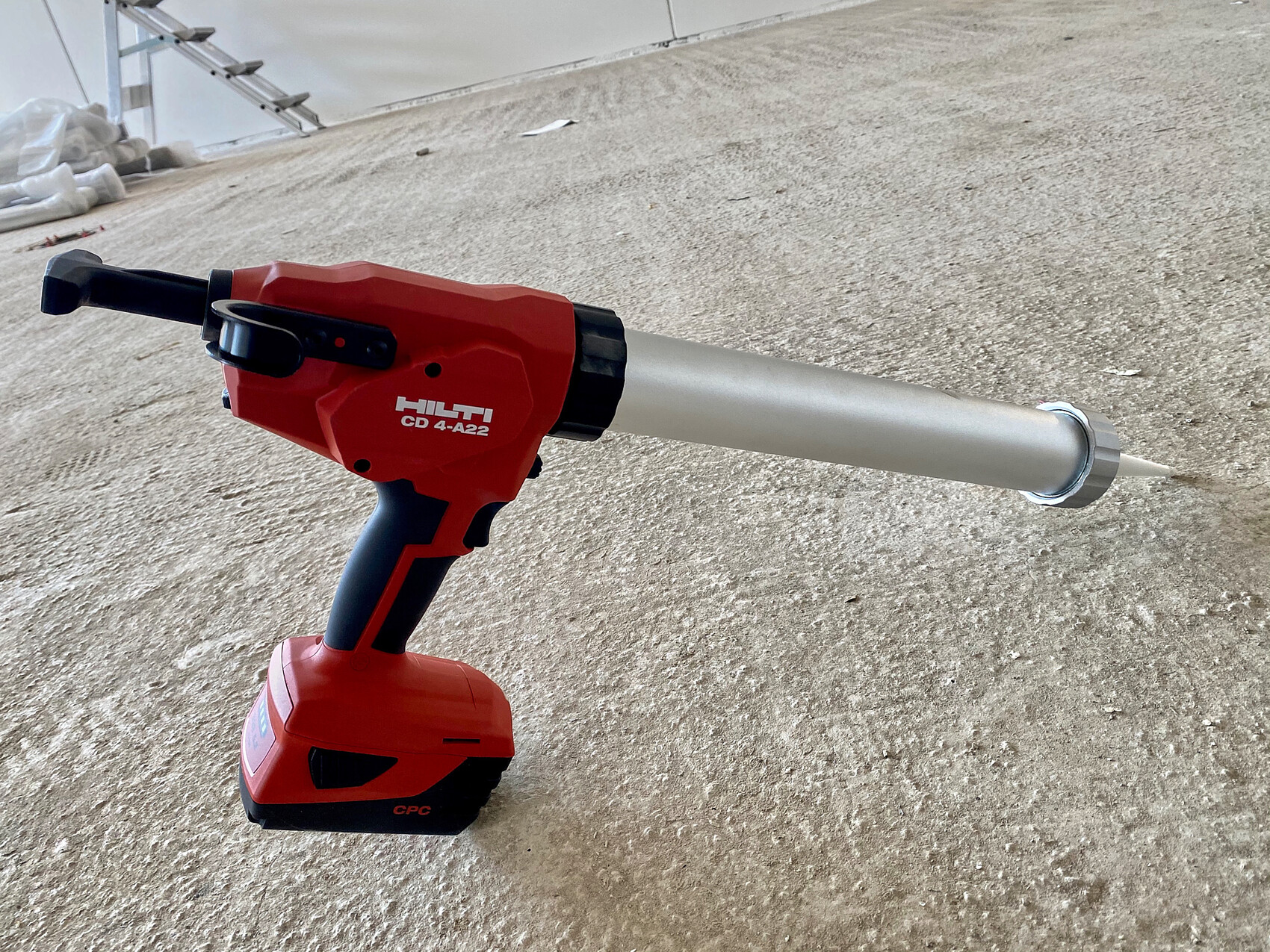 Hilti Akku-Dichtstoffpistole mit langem Metall-Düsenrohr auf rauem Betonboden