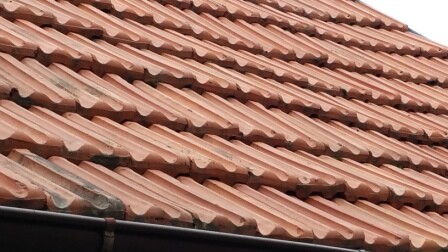 Nahaufnahme roter Dachziegel auf einer Dachfläche mit wellenförmigen Profilen