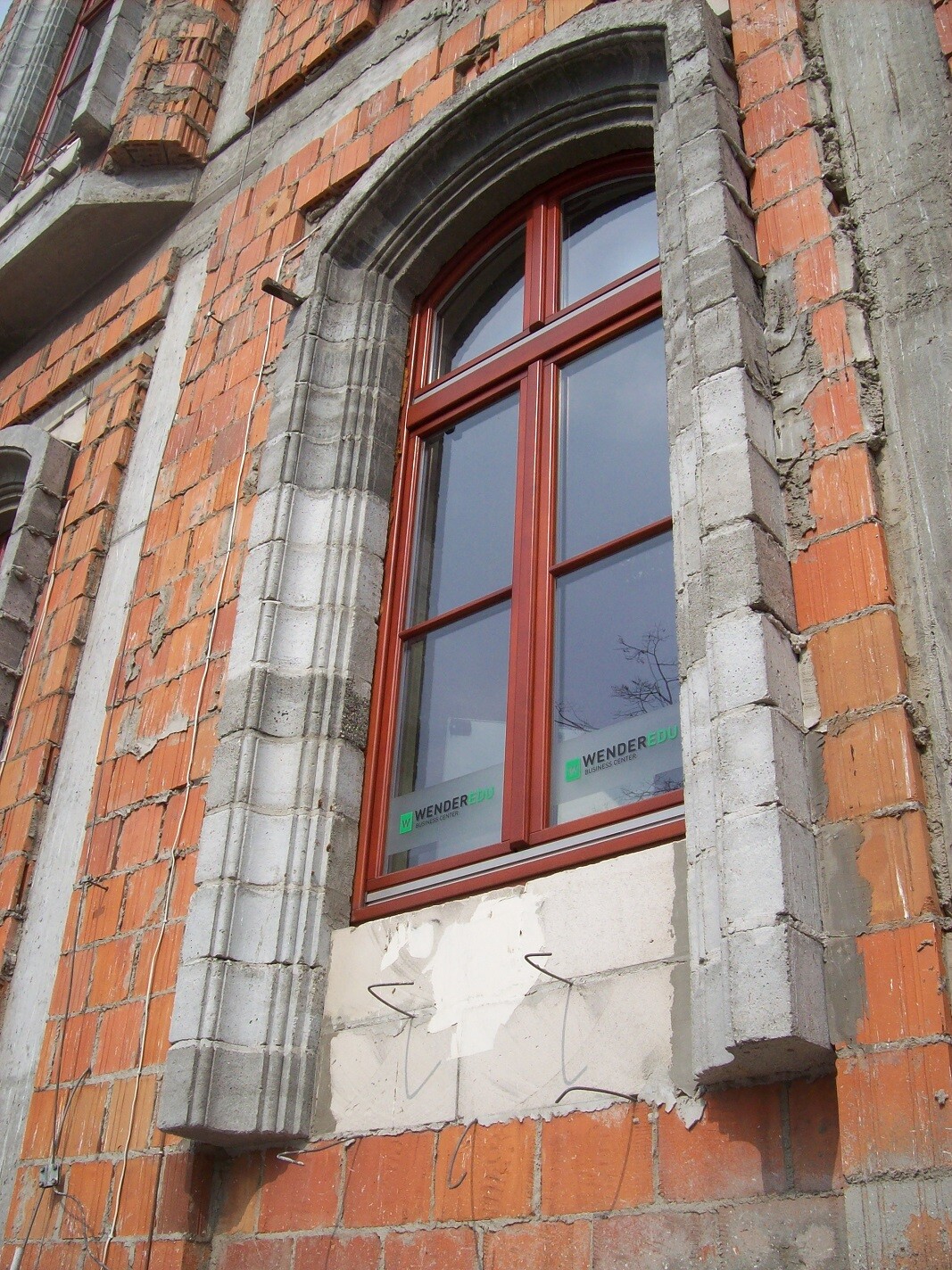 Roter Fensterrahmen in rohem Backsteinbau unter Bauarbeiten