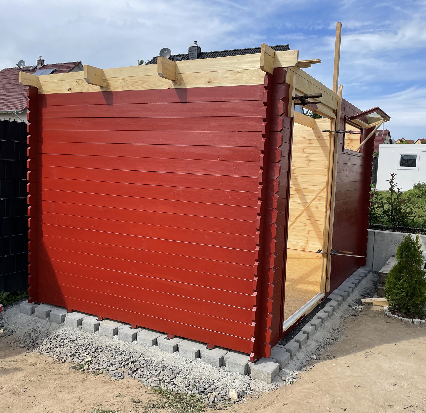 Rot gestrichener Holzschuppen im Bau mit Glas-Tür, Gartenumgebung