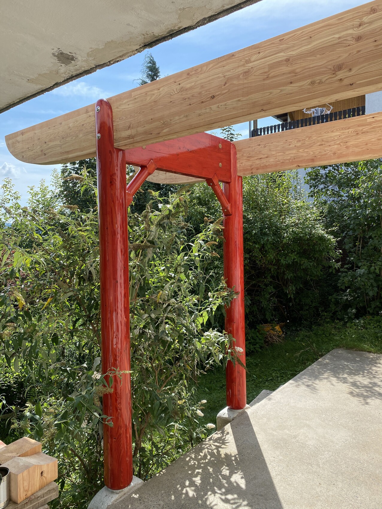 Roter Holzpfosten-Rahmen im Gartenbereich auf einer Baustelle bei Sonnenschein