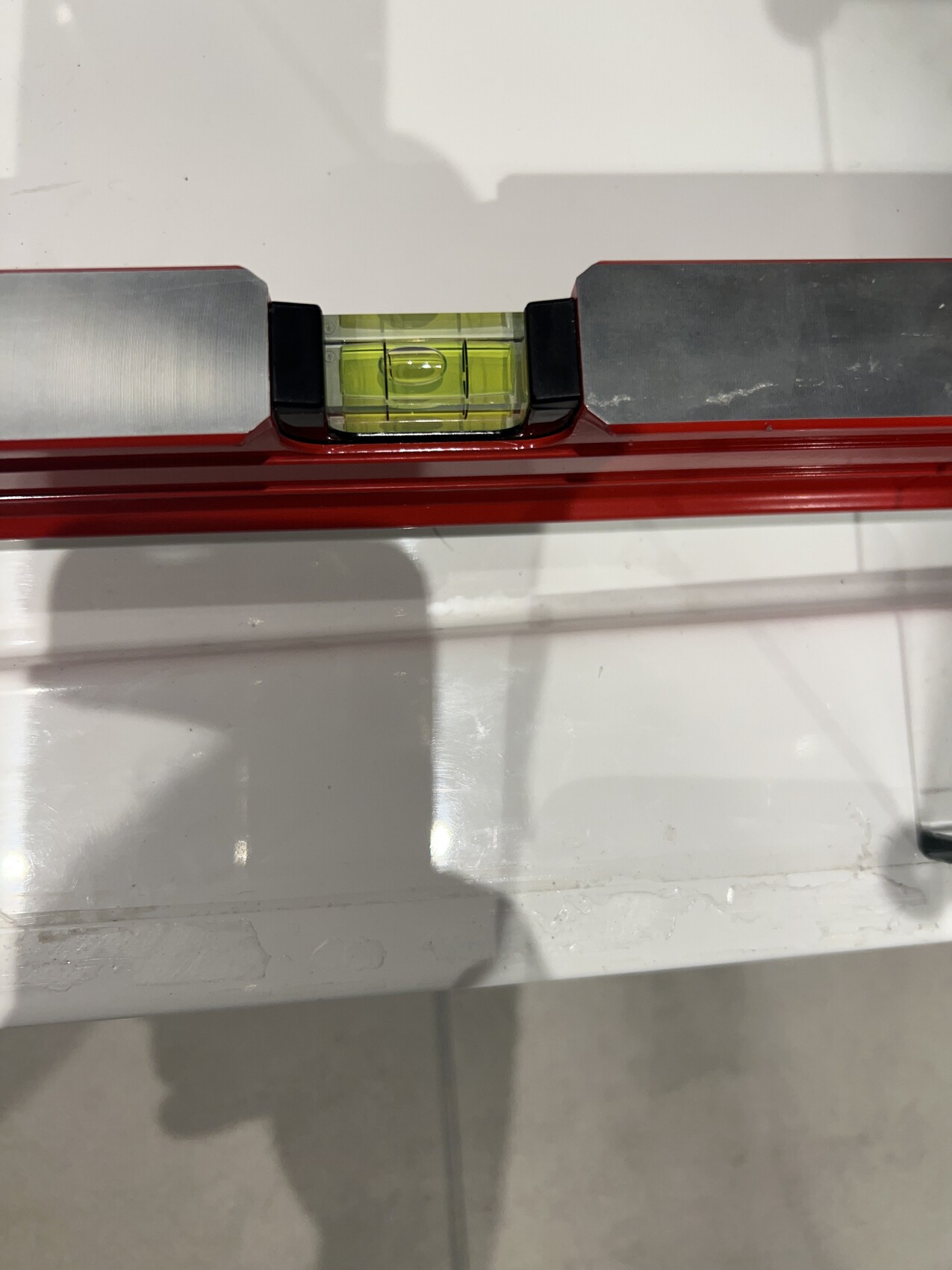 Wasserwaage mit grün-gelbe Blase in rotem Rahmen und Metallkanten.