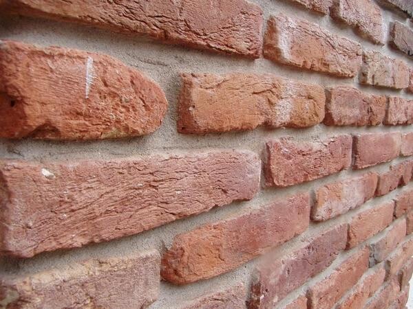 Nahaufnahme einer roten Ziegelwand mit rauer Struktur und Backsteinen