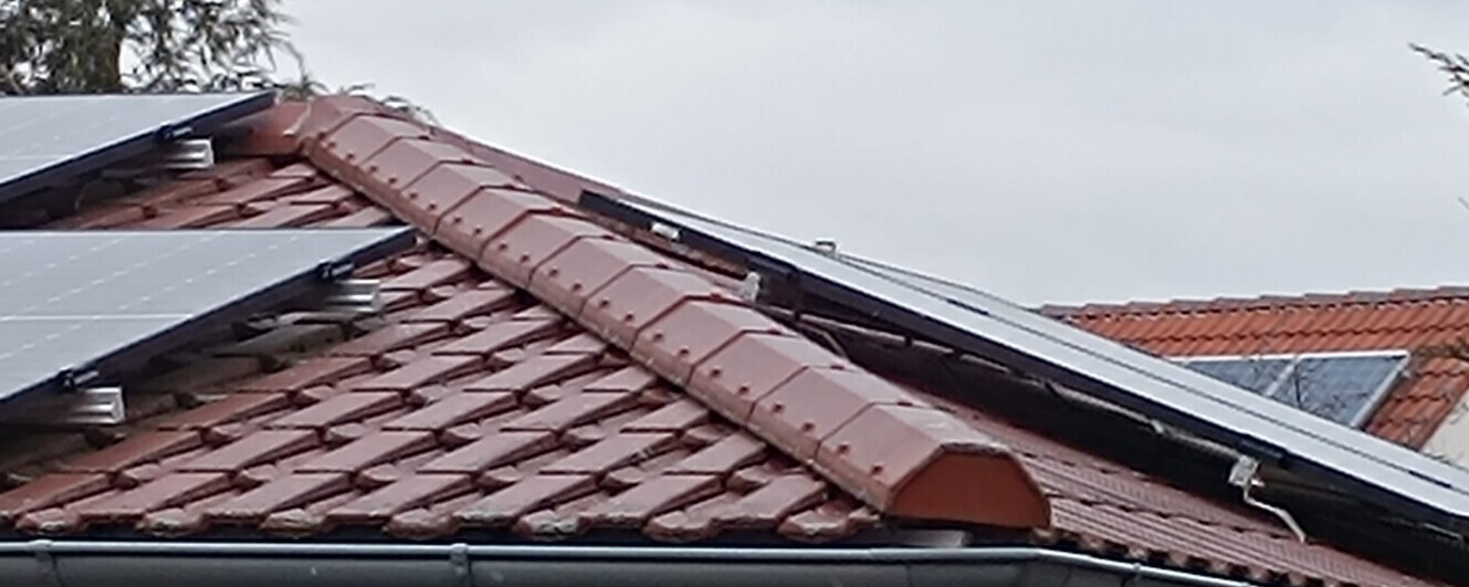 Dach mit roten Tondachziegeln und installierten Solarpanelen.