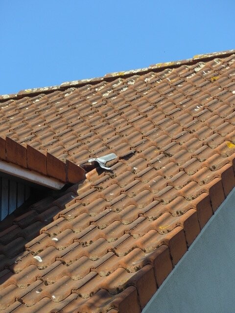 Braunes Ziegeldach mit kleinem Rohr, blauer Himmel im Hintergrund