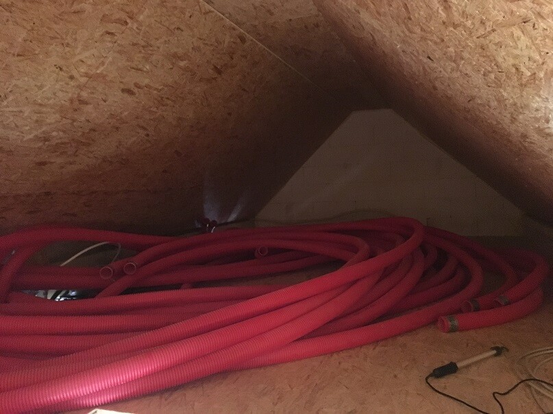 Viele rote Schläuche liegen aufgewickelt auf dem Dachboden.