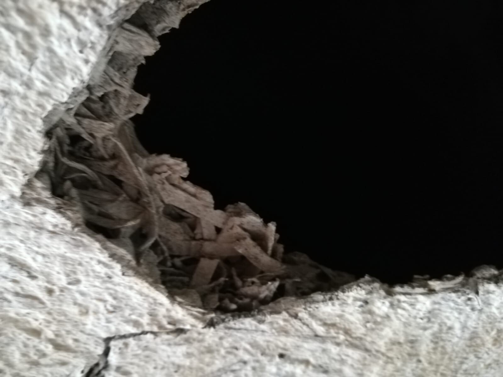 Rohbauwand mit Putzbröckeln und dunklem Hohlraum im Innenbereich
