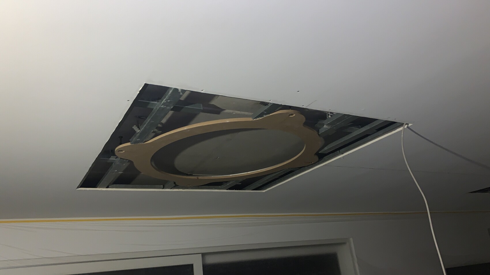 Deckenöffnung mit rundem beigen Ring, dunkler Mitte; Metallrahmen sichtbar, Kabel hängen.