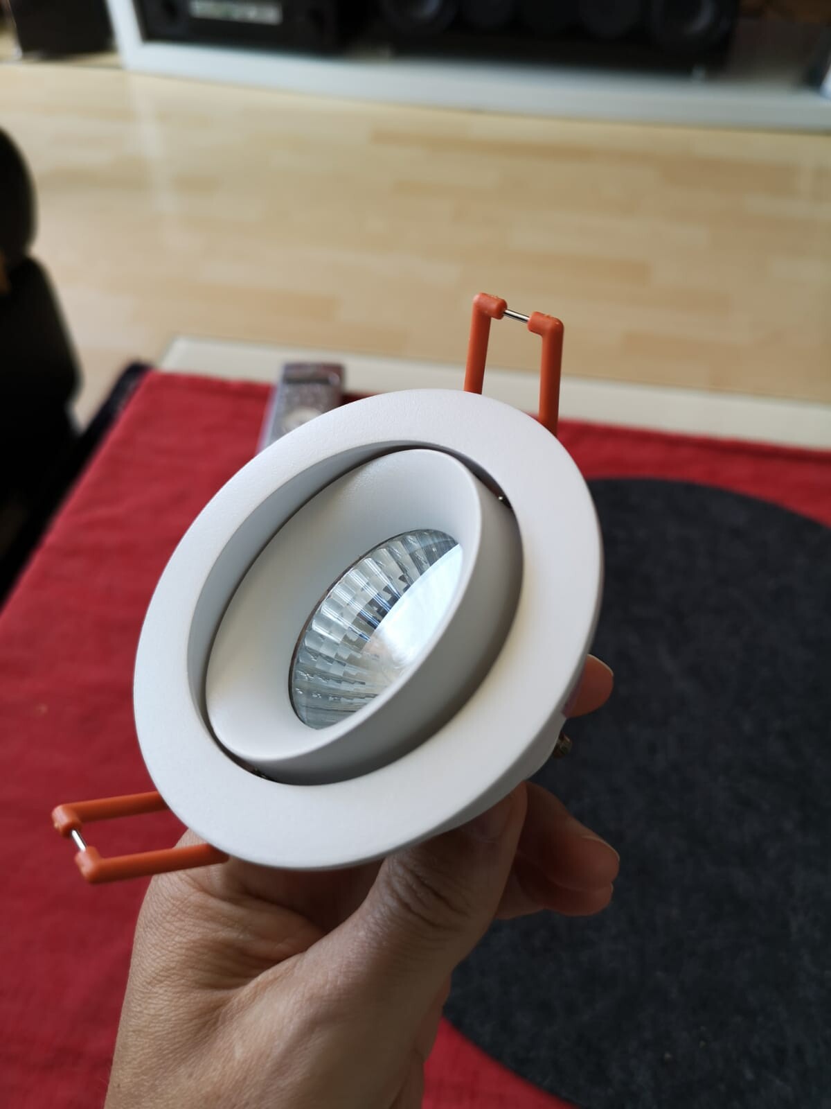 Weißer runder Einbau-LED-Downlight mit Reflektor, orange Halteklammern, in der Hand
