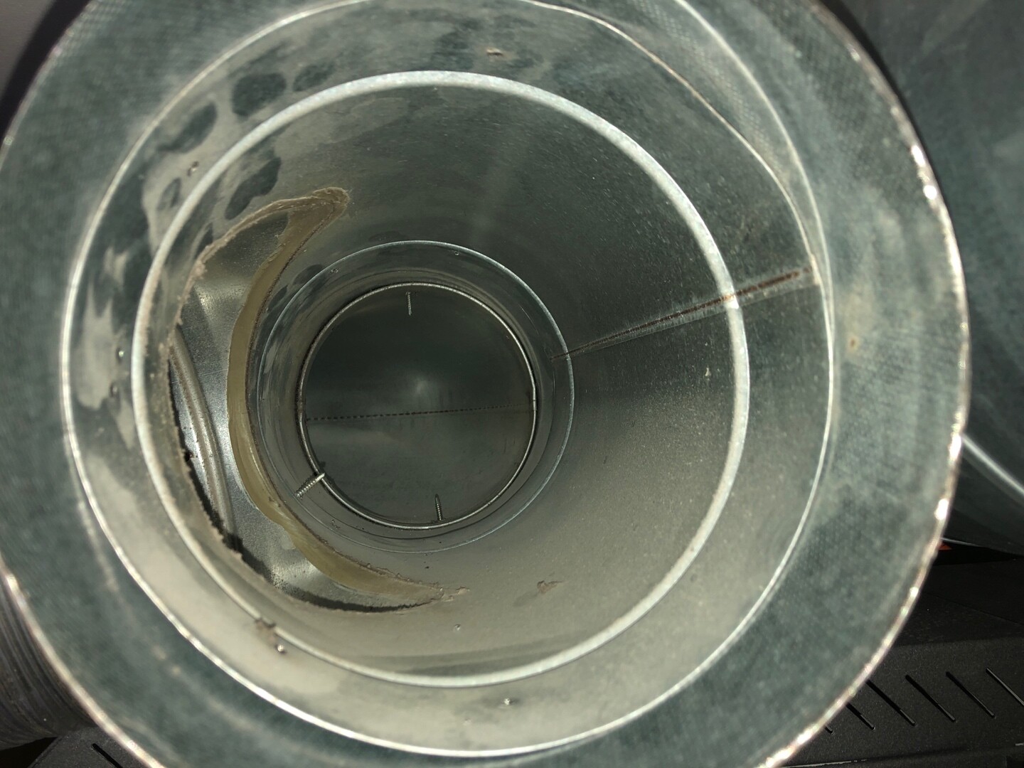 Innenansicht eines runden Metallkanals/Lüftungsschachts mit mehreren ringsförmigen Ringen.