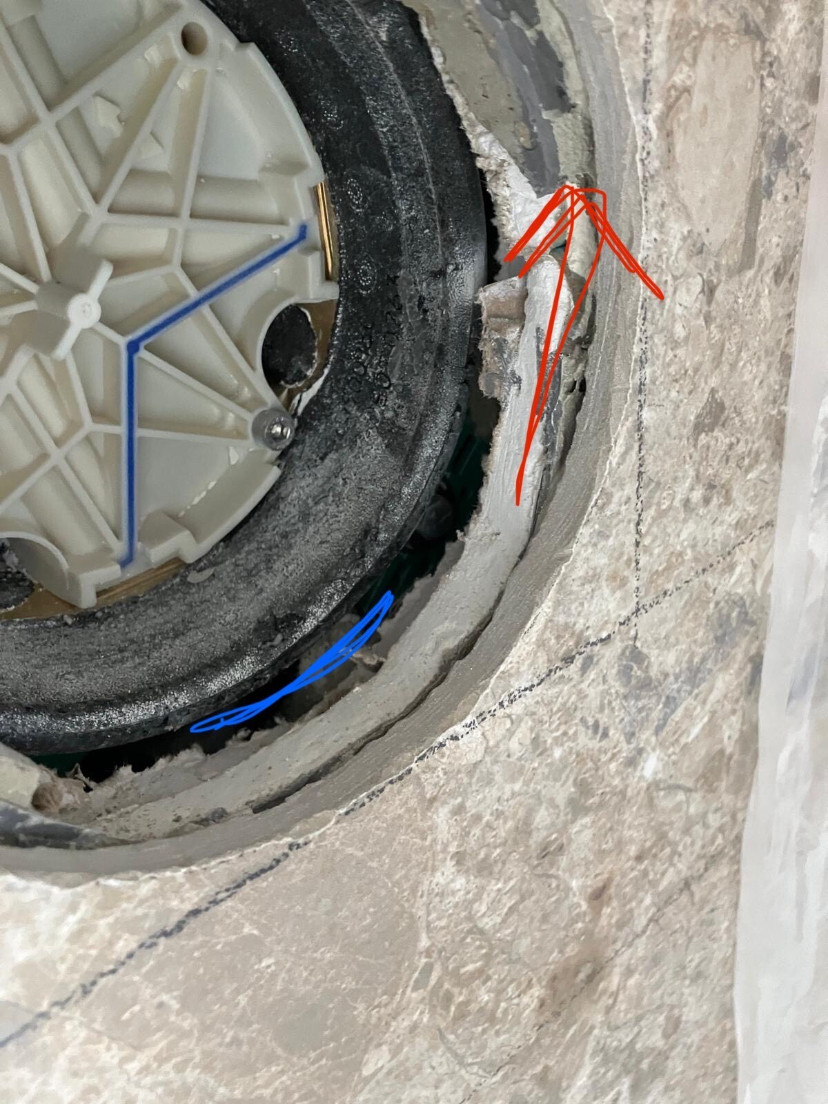 Rundes Kunststoffteil in Badezimmerwand mit Mörtel umgeben, rote Markierung hebt Riss hervor