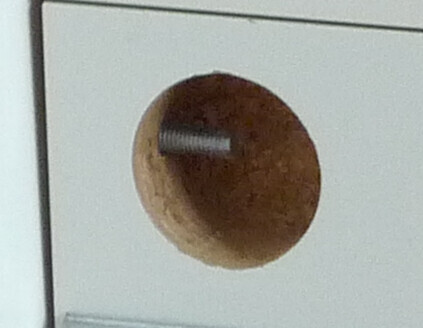 Nahaufnahme eines runden Bohrlochs in hellen Möbelplatten mit Schraubbolzen.